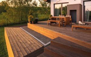 Terrasse en bois composite sur deux niveaux posée sur plots réglables, avec marche, table et bancs devant une maison moderne