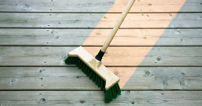 nettoyage au balai d'une terrasse sur plots en bois exotique