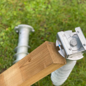 Vis pieux en acier galvanisé avec support en U et poteau en bois carré posés sur l’herbe