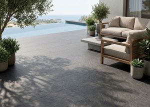 Carrelage extérieur effet pierre gris anthracite sur terrasse au bord d'une piscine avec salon de jardin
